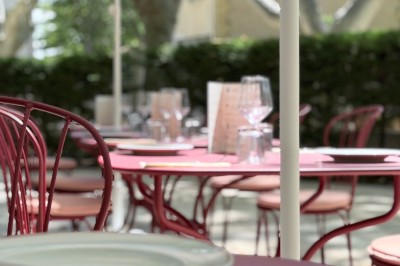 Table dressée avec assiettes, couverts, verres, serviettes et menu sur un set de table rond dans un restaurant.