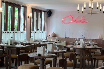 Table dressée avec assiettes, couverts, verres, serviettes et menu sur un set de table rond dans un restaurant.