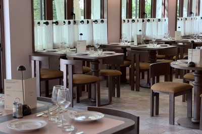 Table dressée avec assiettes, couverts, verres, serviettes et menu sur un set de table rond dans un restaurant.
