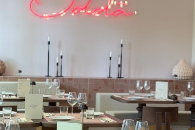 Table dressée avec assiettes, couverts, verres, serviettes et menu sur un set de table rond dans un restaurant.