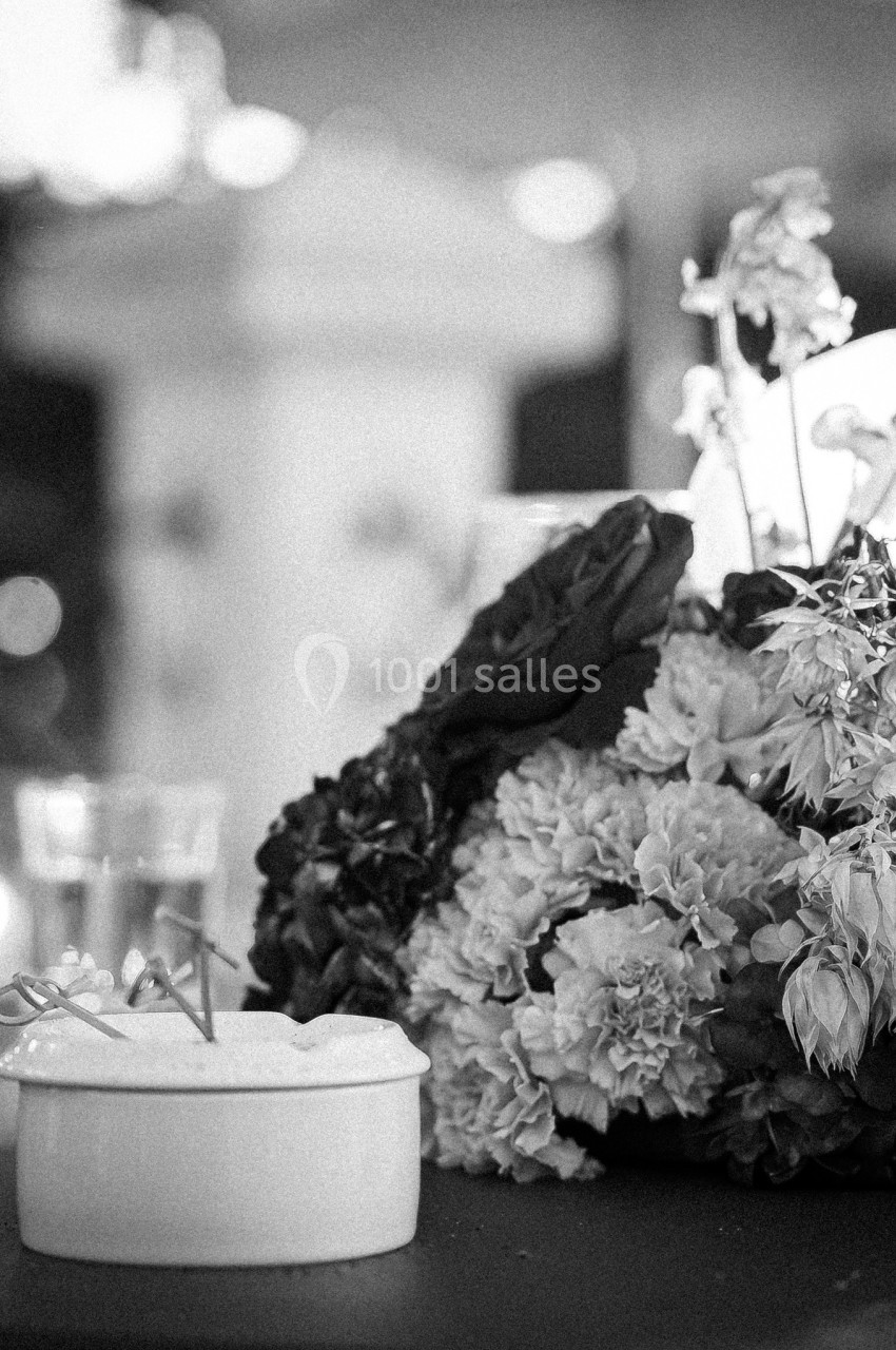 Bouquet de fleurs fanées posé sur une table, éclairé par une lumière douce dans un environnement flou.