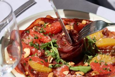 Panier en osier rempli de fruits variés, dont ananas, pommes, oranges et citrons, posé sur une nappe blanche.