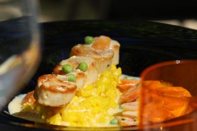 Panier en osier rempli de fruits variés, dont ananas, pommes, oranges et citrons, posé sur une nappe blanche.