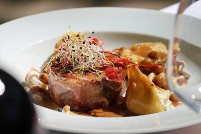 Panier en osier rempli de fruits variés, dont ananas, pommes, oranges et citrons, posé sur une nappe blanche.