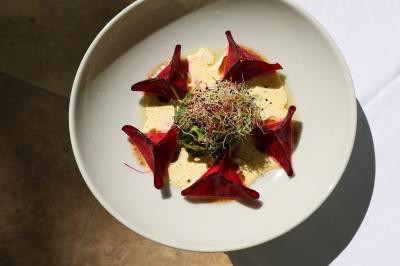 Panier en osier rempli de fruits variés, dont ananas, pommes, oranges et citrons, posé sur une nappe blanche.