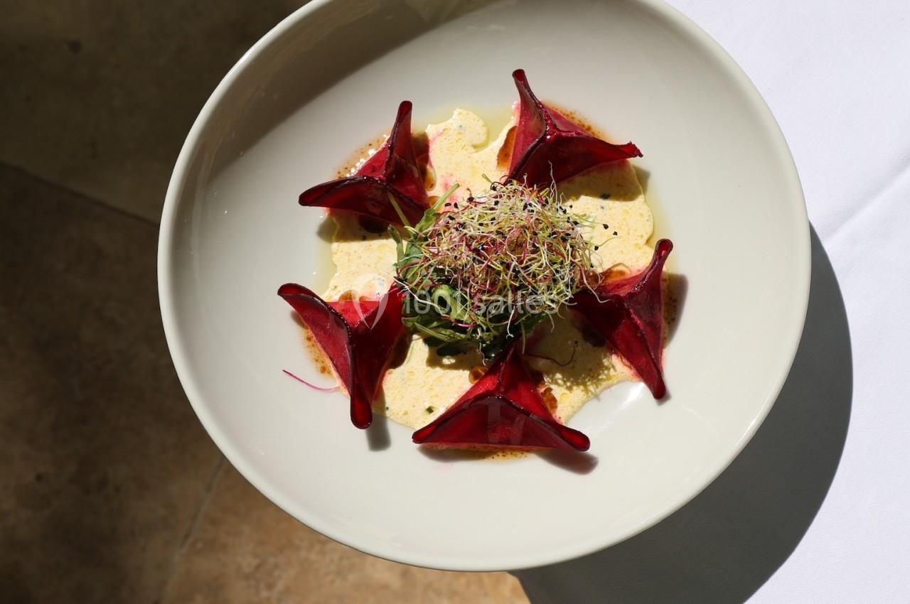 Assiette de betteraves rouges en tranches, garnie de pousses et servie sur une sauce claire, vue en lumière naturelle.