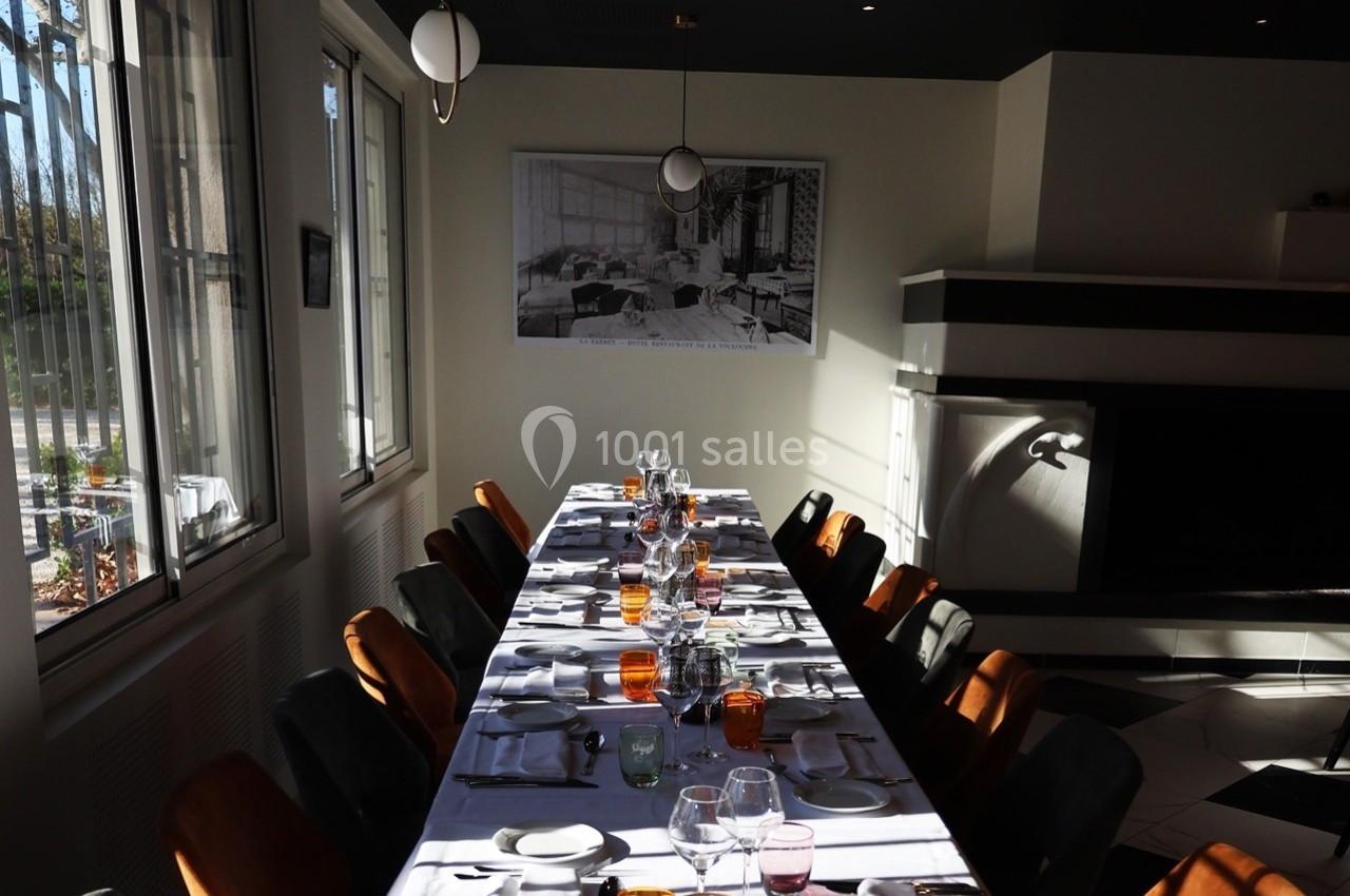 Table dressée avec vaisselle colorée dans une salle lumineuse, près d'une cheminée et de grandes fenêtres.