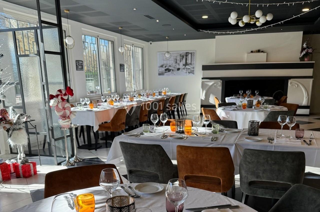 Salle de restaurant lumineuse avec tables dressées, chaises en cuir, grandes fenêtres et décoration festive.