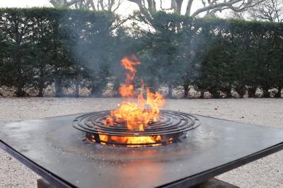Panier en osier rempli de fruits variés, dont ananas, pommes, oranges et citrons, posé sur une nappe blanche.