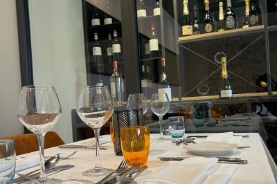 Panier en osier rempli de fruits variés, dont ananas, pommes, oranges et citrons, posé sur une nappe blanche.