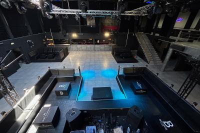 Espace lounge sombre avec canapés en cuir, tables basses marquées ’Cîroc’ et décoration lumineuse en forme d'astronaute.