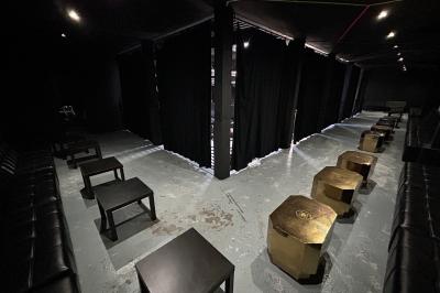 Espace lounge sombre avec canapés en cuir, tables basses marquées ’Cîroc’ et décoration lumineuse en forme d'astronaute.