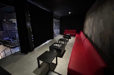 Espace lounge sombre avec canapés en cuir, tables basses marquées ’Cîroc’ et décoration lumineuse en forme d'astronaute.