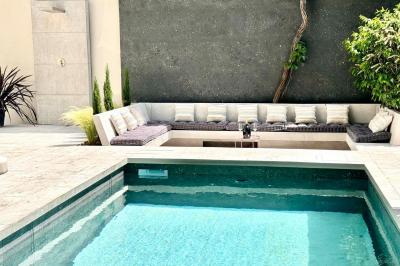 Salle de bien-être avec sauna vitré éclairé en bleu, projecteurs lumineux et ambiance tamisée.