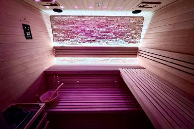 Salle de bien-être avec sauna vitré éclairé en bleu, projecteurs lumineux et ambiance tamisée.