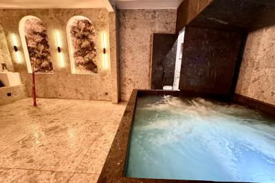 Salle de bien-être avec sauna vitré éclairé en bleu, projecteurs lumineux et ambiance tamisée.