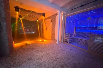 Salle de bien-être avec sauna vitré éclairé en bleu, projecteurs lumineux et ambiance tamisée.