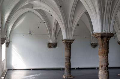 Salle avec des murs en pierre et poutres apparentes, aménagée pour une cérémonie avec des invités assis sur des chaises…