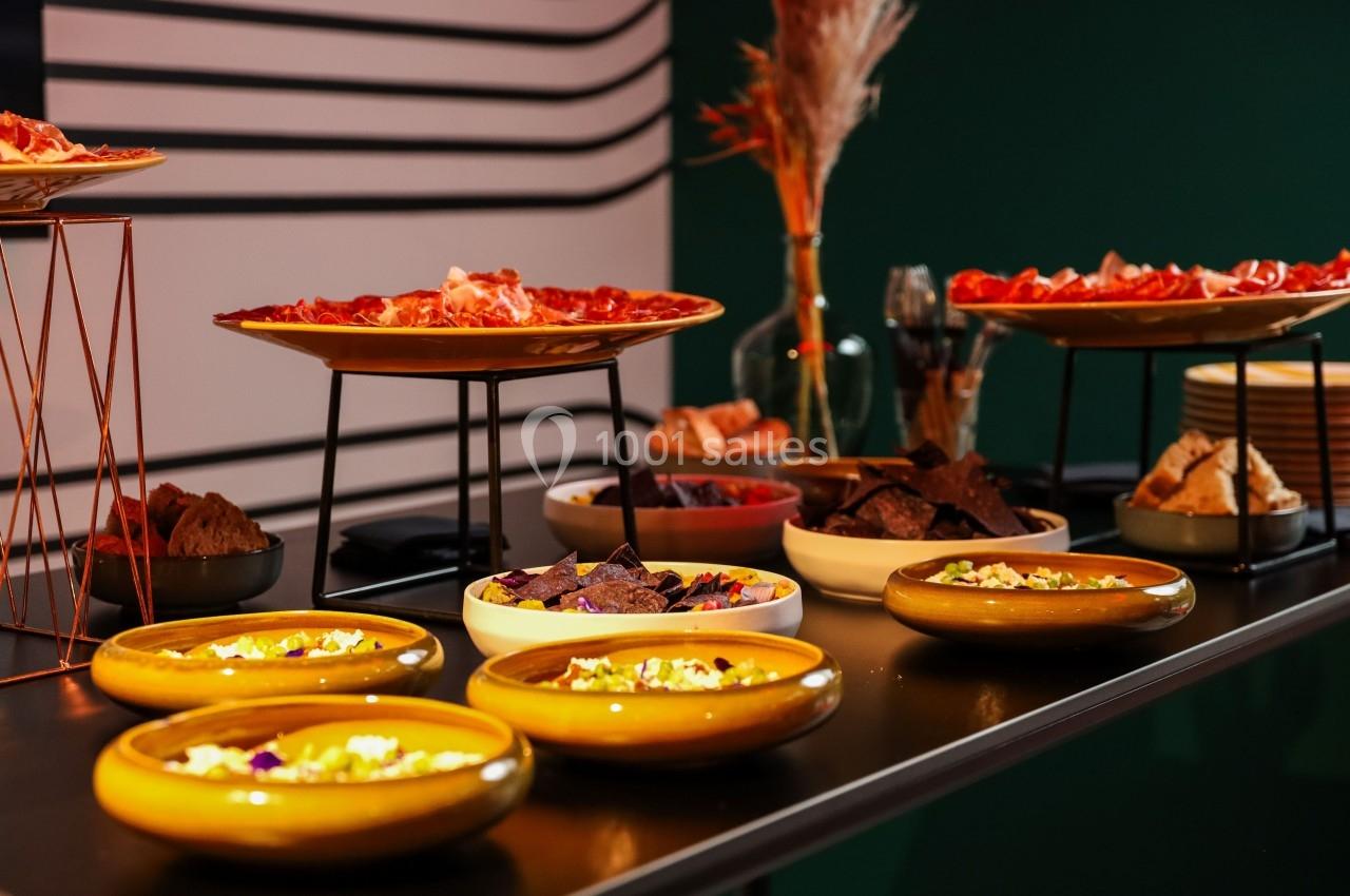 Table garnie de plats variés, incluant charcuteries, chips et sauces, dans un cadre moderne et chaleureux.