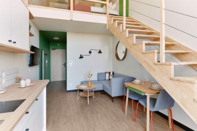 Un couple célèbre son mariage sur une petite scène décorée de voiles et de feuillages, devant une fresque colorée.