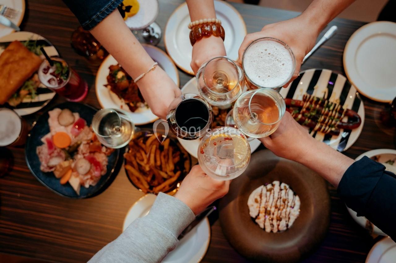 Des personnes trinquent avec des verres au-dessus d'une table garnie de plats variés.