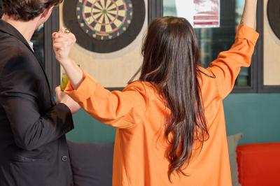 Un couple célèbre son mariage sur une petite scène décorée de voiles et de feuillages, devant une fresque colorée.
