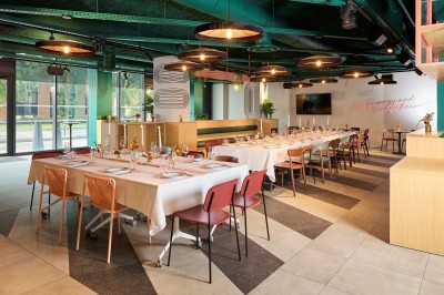 Un couple célèbre son mariage sur une petite scène décorée de voiles et de feuillages, devant une fresque colorée.