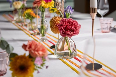 Un couple célèbre son mariage sur une petite scène décorée de voiles et de feuillages, devant une fresque colorée.