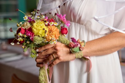 Un couple célèbre son mariage sur une petite scène décorée de voiles et de feuillages, devant une fresque colorée.