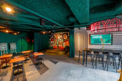 Un couple célèbre son mariage sur une petite scène décorée de voiles et de feuillages, devant une fresque colorée.