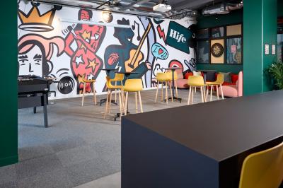 Un couple célèbre son mariage sur une petite scène décorée de voiles et de feuillages, devant une fresque colorée.