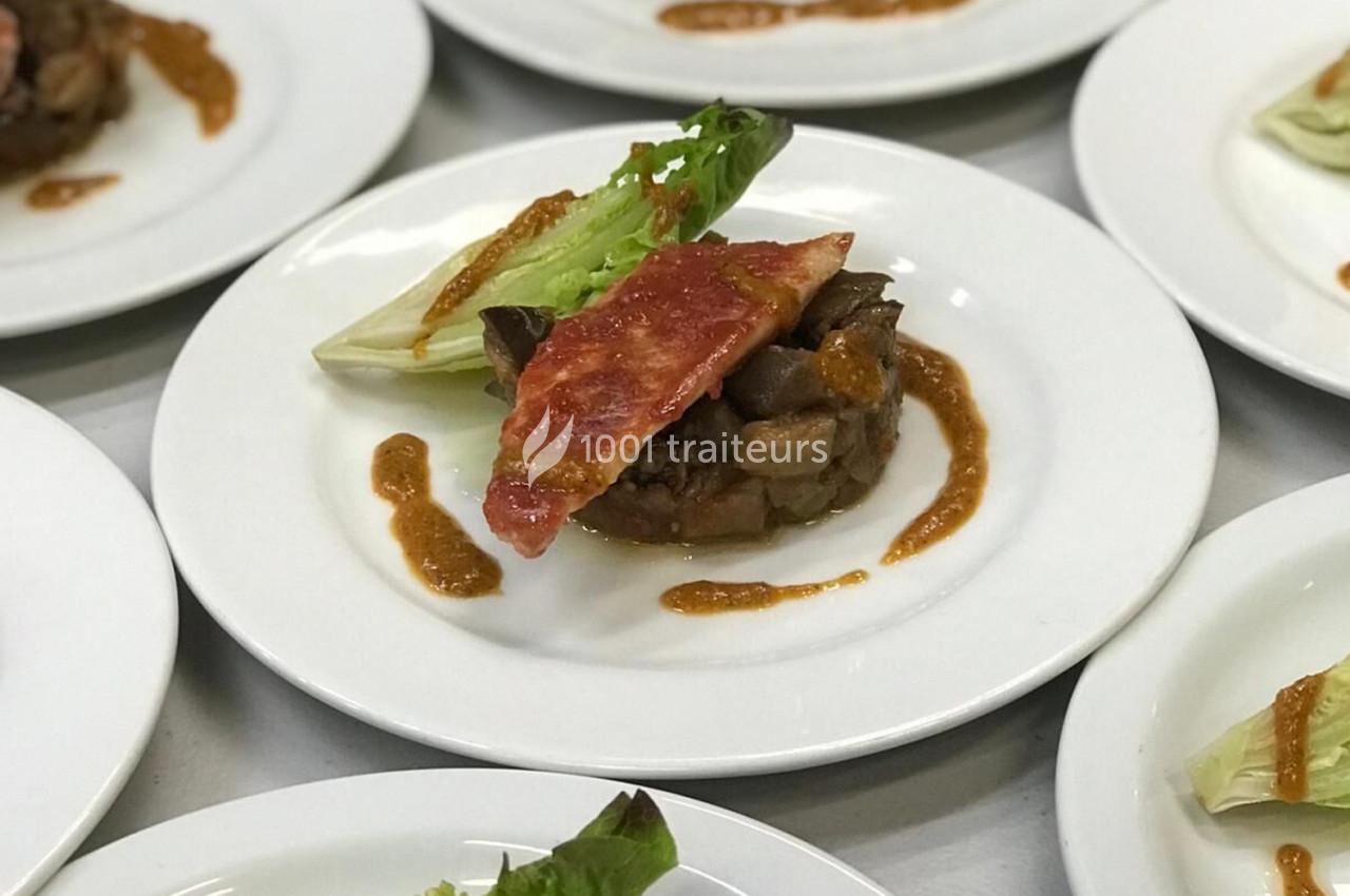 Assiette contenant une présentation soignée de légumes, salade, tranche de bacon et sauce disposée en décoration.