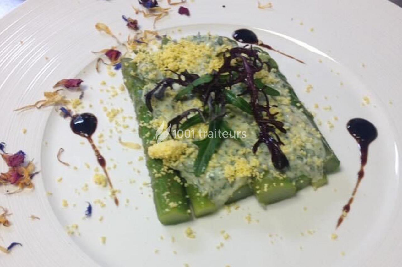 Assiette d'asperges garnies de sauce crémeuse, herbes fraîches, miettes d'œuf et décorations florales.