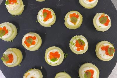 Homme en veste de chef blanche, debout devant une architecture en pierre et des grilles métalliques.