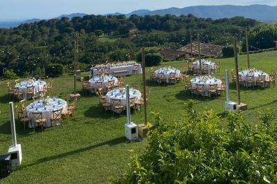 Tables rondes dressées pour un événement en plein air sur une pelouse, avec vue sur des collines verdoyantes.