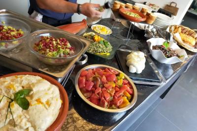 Homme en veste de chef blanche, debout devant une architecture en pierre et des grilles métalliques.