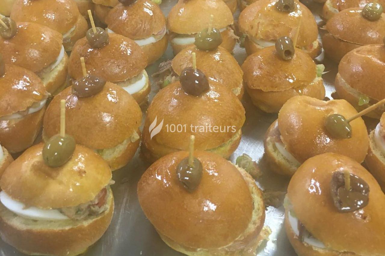 Petits sandwichs ronds garnis de thon, œufs et olives vertes, présentés sur un plateau.