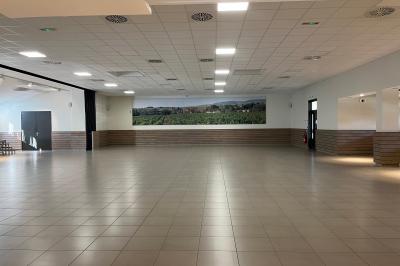 Bâtiment moderne avec façade orange, toit en tuiles, entrée couverte et deux jardinières en tonneaux sur roulettes.