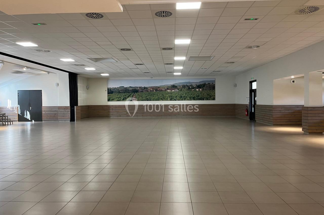 Salle spacieuse avec carrelage clair, plafond à dalles blanches et fresque murale représentant un paysage rural.