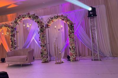 Bâtiment moderne avec façade noire, terrasse aménagée, murs végétalisés et sculptures, sous un ciel nuageux.