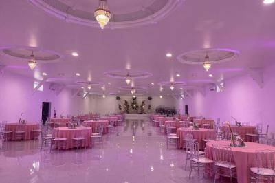 Bâtiment moderne avec façade noire, terrasse aménagée, murs végétalisés et sculptures, sous un ciel nuageux.