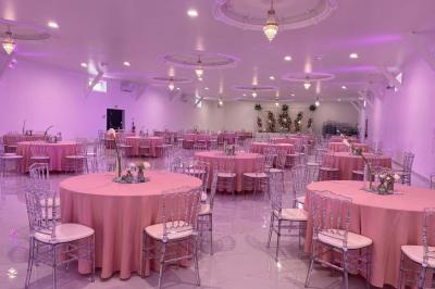 Bâtiment moderne avec façade noire, terrasse aménagée, murs végétalisés et sculptures, sous un ciel nuageux.