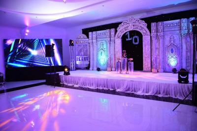 Bâtiment moderne avec façade noire, terrasse aménagée, murs végétalisés et sculptures, sous un ciel nuageux.