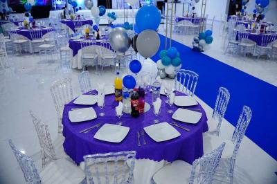 Bâtiment moderne avec façade noire, terrasse aménagée, murs végétalisés et sculptures, sous un ciel nuageux.