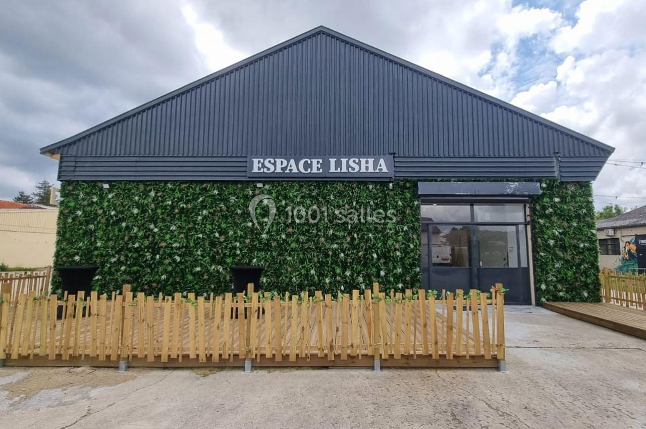 Façade d'un bâtiment moderne avec un mur végétalisé, une clôture en bois et une enseigne ’Espace Lisha’.