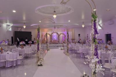 Bâtiment moderne avec façade noire, terrasse aménagée, murs végétalisés et sculptures, sous un ciel nuageux.