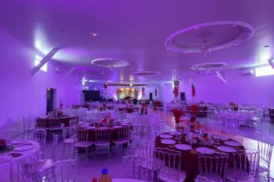 Bâtiment moderne avec façade noire, terrasse aménagée, murs végétalisés et sculptures, sous un ciel nuageux.