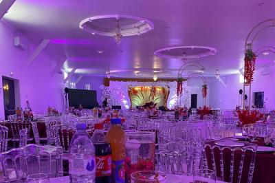 Bâtiment moderne avec façade noire, terrasse aménagée, murs végétalisés et sculptures, sous un ciel nuageux.