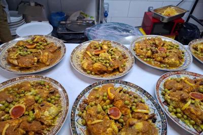 Bâtiment moderne avec façade noire, terrasse aménagée, murs végétalisés et sculptures, sous un ciel nuageux.