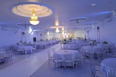 Bâtiment moderne avec façade noire, terrasse aménagée, murs végétalisés et sculptures, sous un ciel nuageux.